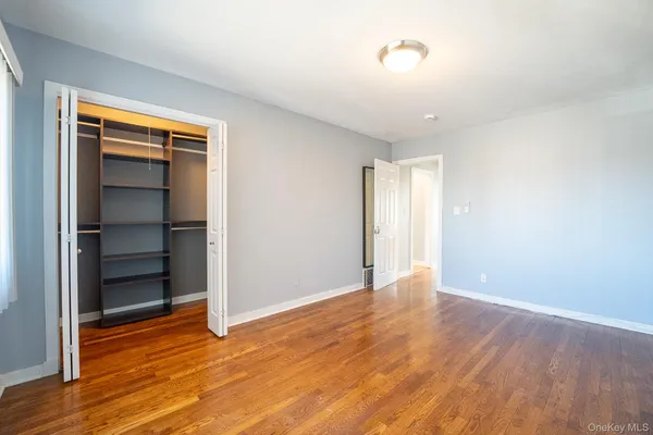 a view of an empty room with wooden floor closet and fire place
