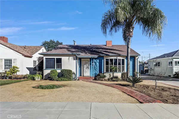 a front view of a house with a yard and potted plants