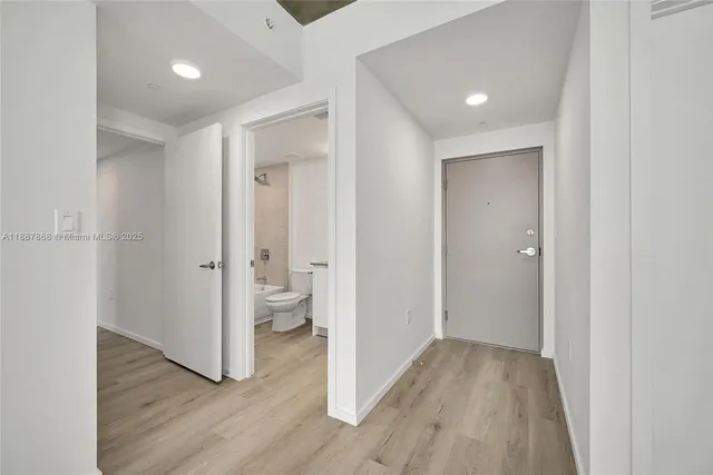 a view of a hallway with wooden floor and a bathroom