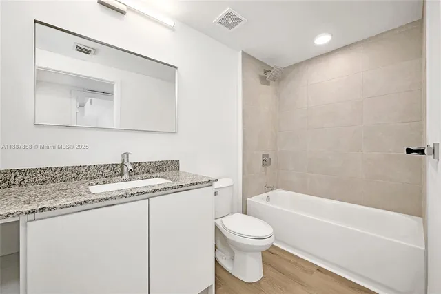 a bathroom with a granite countertop sink a toilet and bathtub