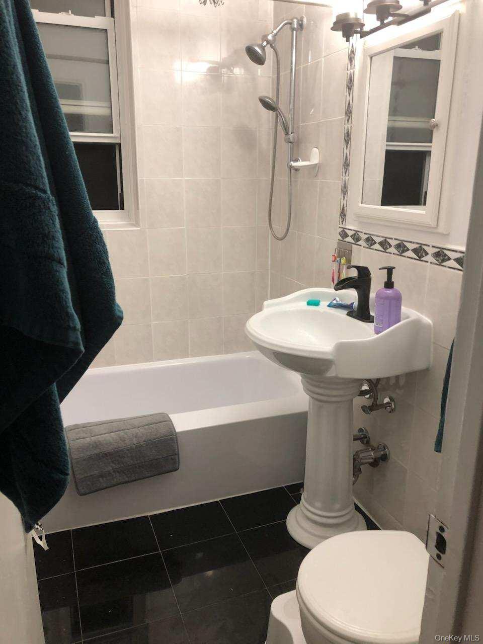 3176 Decatur Avenue, Unit 2H Bronx, NY 10467 - Photo 2 of 11 a bathroom with a sink a toilet a mirror and shower