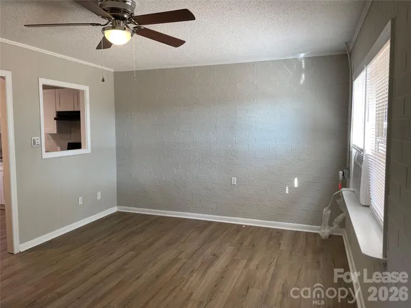 an empty room with wooden floor fan and windows