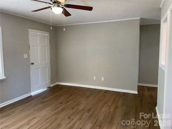 an empty room with wooden floor fan and windows