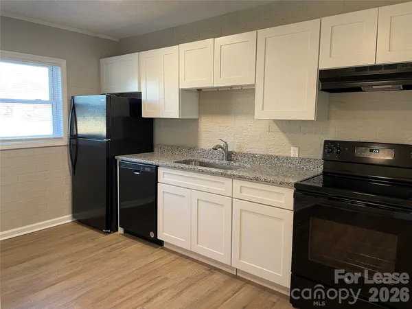 a kitchen with granite countertop white cabinets and black appliances