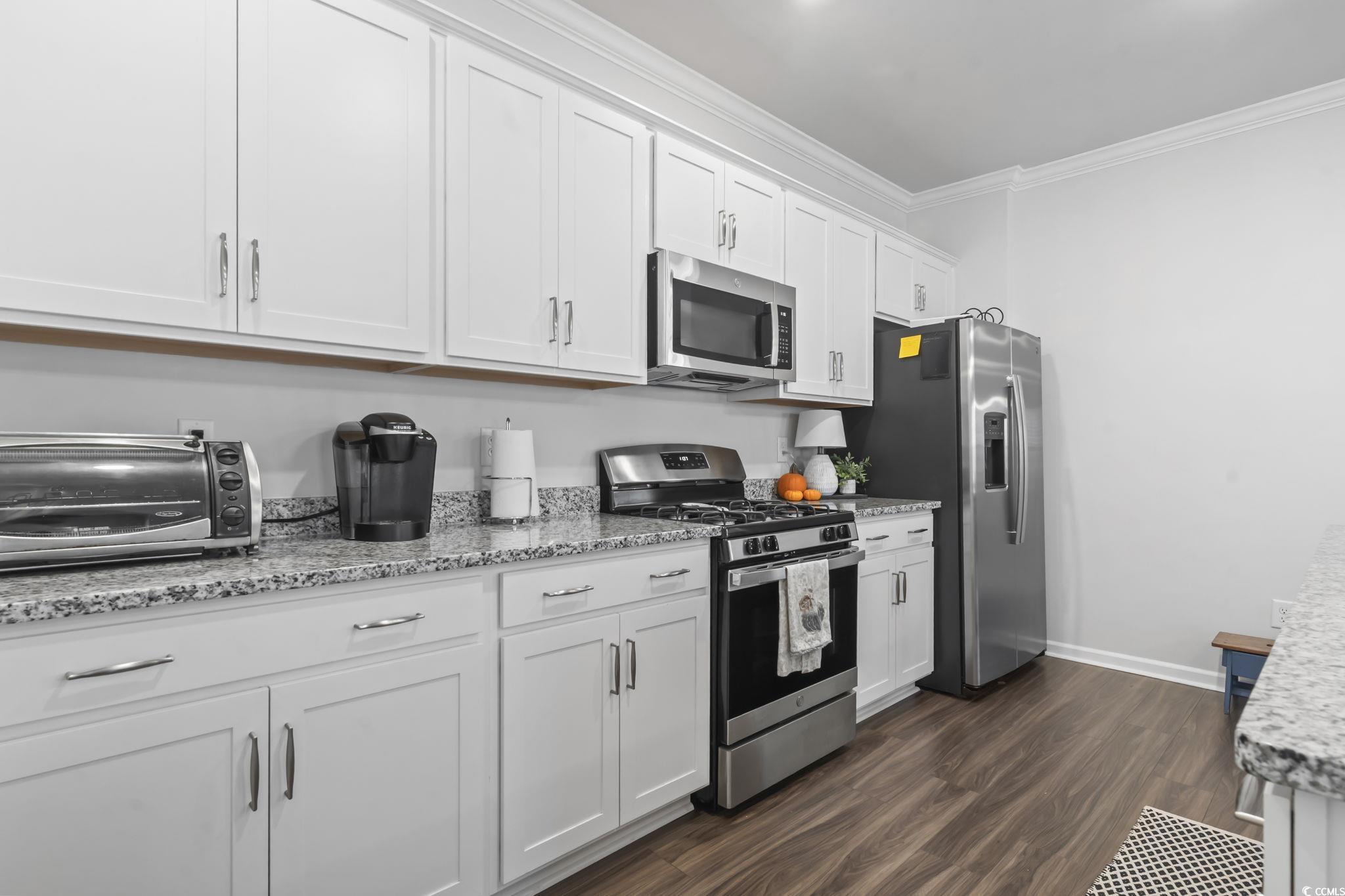 1310 Boswell Court Conway, SC 29526 - Photo 19 of 35 Kitchen with stainless steel appliances, white cabinets, dark wood finished floors, ornamental molding, and light stone counters