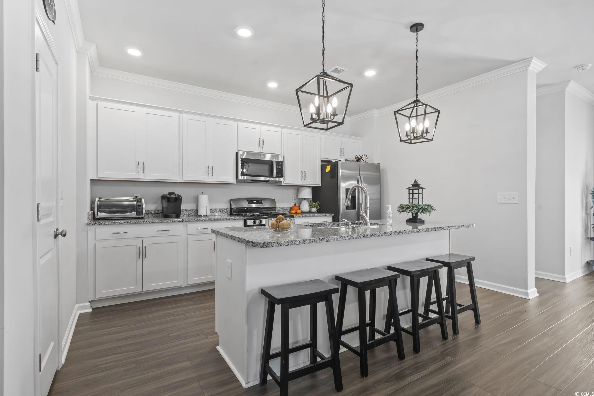 1310 Boswell Court Conway, SC 29526 - Photo 27 of 35 Kitchen with a kitchen breakfast bar, a center island with sink, ornamental molding, decorative light fixtures, and white cabinets