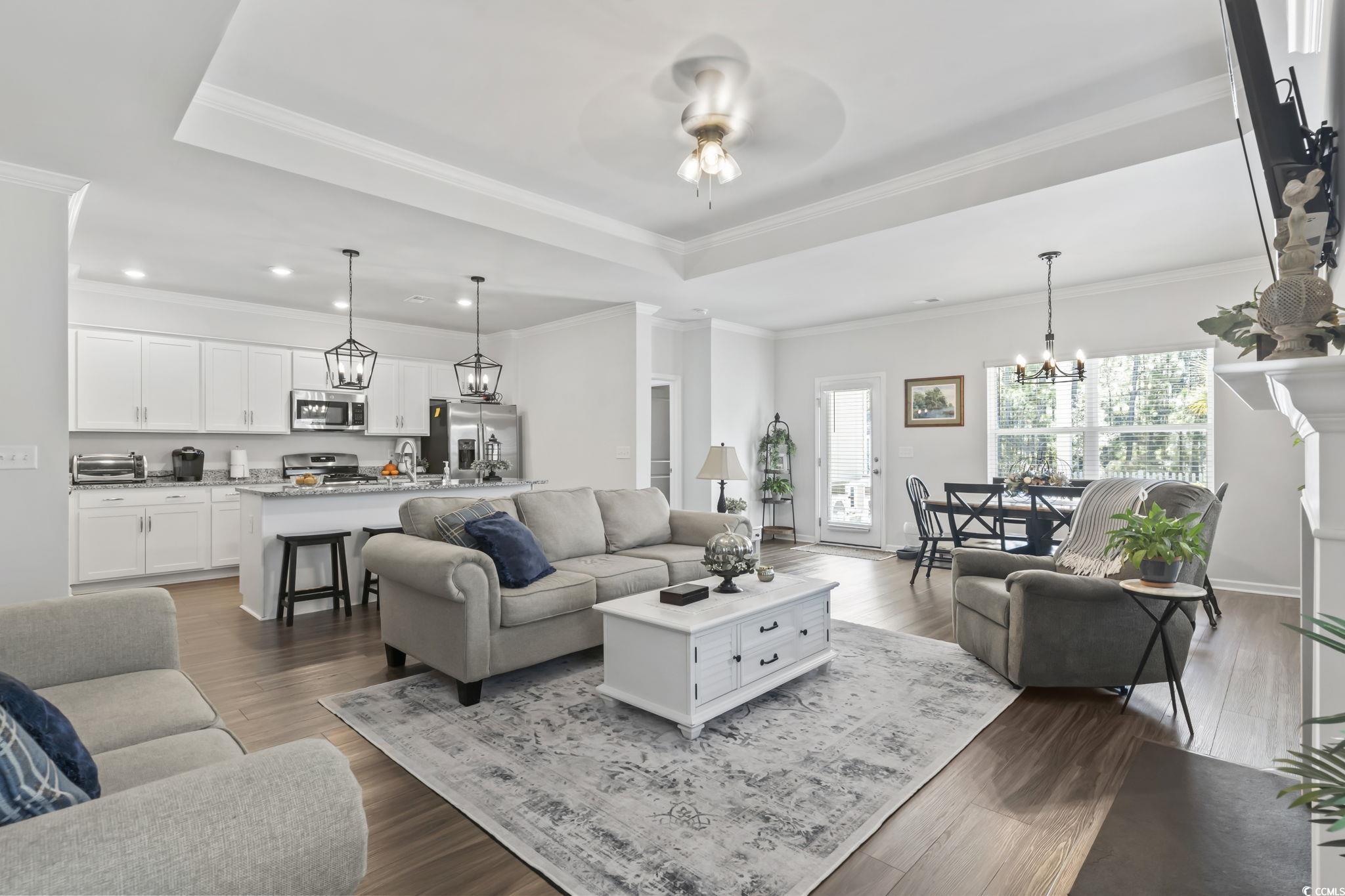 1310 Boswell Court Conway, SC 29526 - Photo 28 of 35 Living room featuring a chandelier, crown molding, dark wood-style flooring, ceiling fan, and a raised ceiling