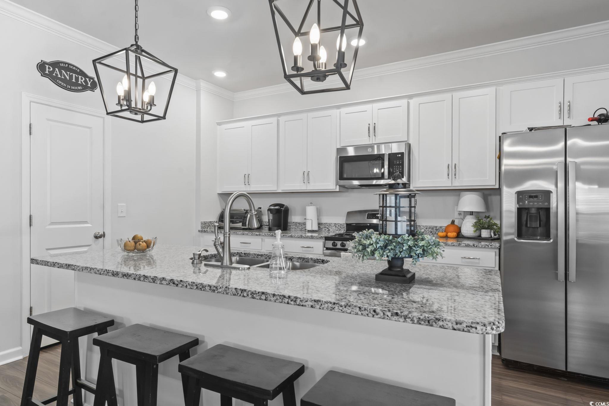 1310 Boswell Court Conway, SC 29526 - Photo 3 of 35 Kitchen featuring stainless steel appliances, dark wood finished floors, an island with sink, white cabinets, and crown molding
