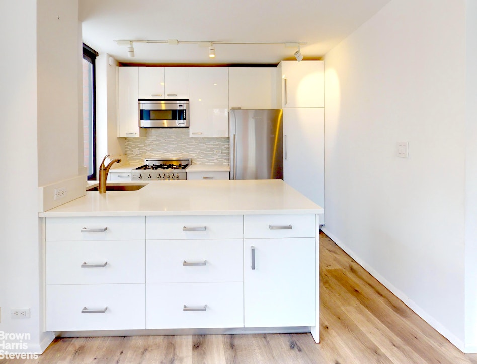 200 Rector Place, Unit 8U Manhattan, NY 10280 - Photo 12 of 25 a kitchen with granite countertop white cabinets and refrigerator