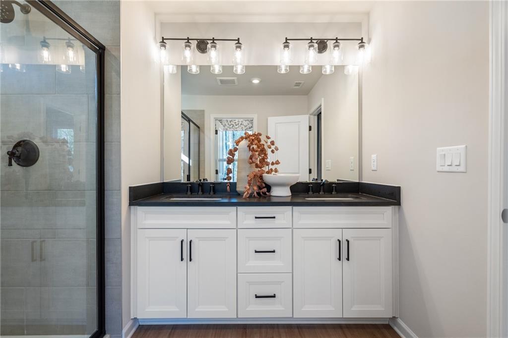 710 Smokey Quartz Way Kennesaw, GA 30144 - Photo 67 of 76 a bathroom with a granite countertop shower a mirror and a sink