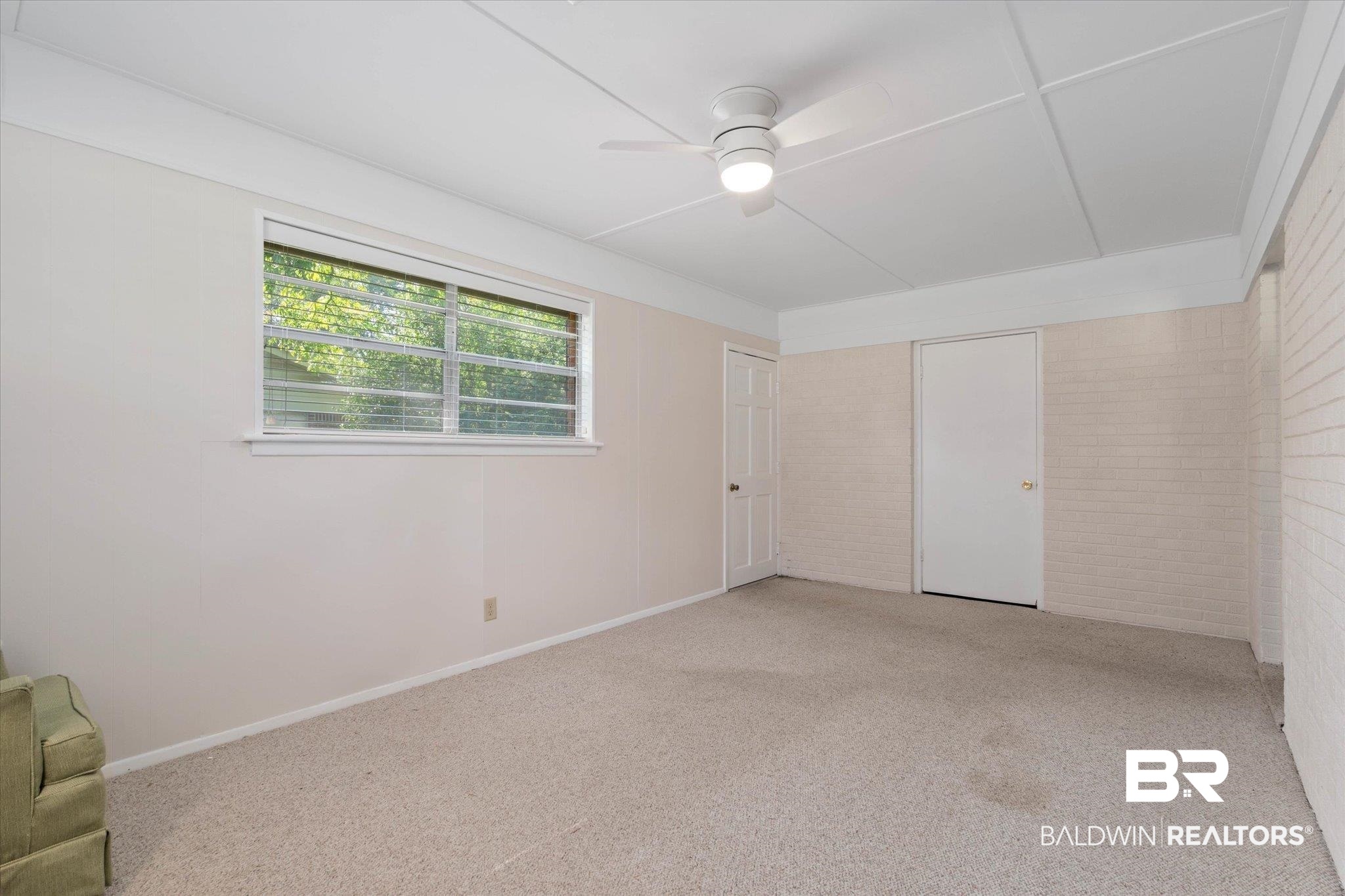 423 First Avenue Saraland, AL 36571 - Photo 6 of 20 Empty room with brick wall, a ceiling fan, and light carpet