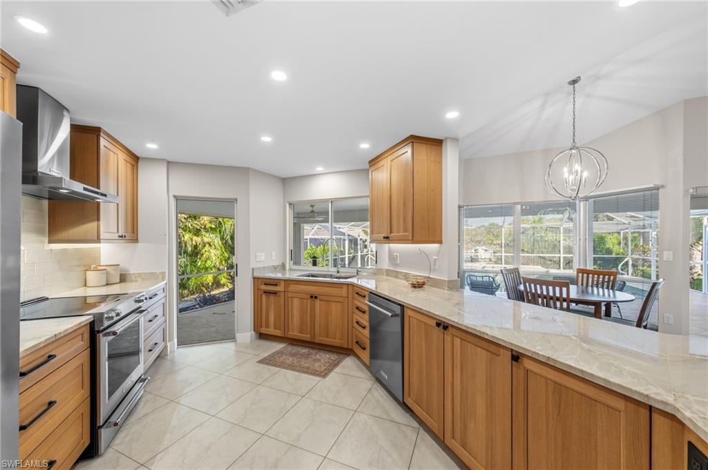 4724 Riverside Drive Estero, FL 33928 - Photo 10 of 44 a large kitchen with stainless steel appliances a large counter top a stove a sink a oven a dining table and chairs