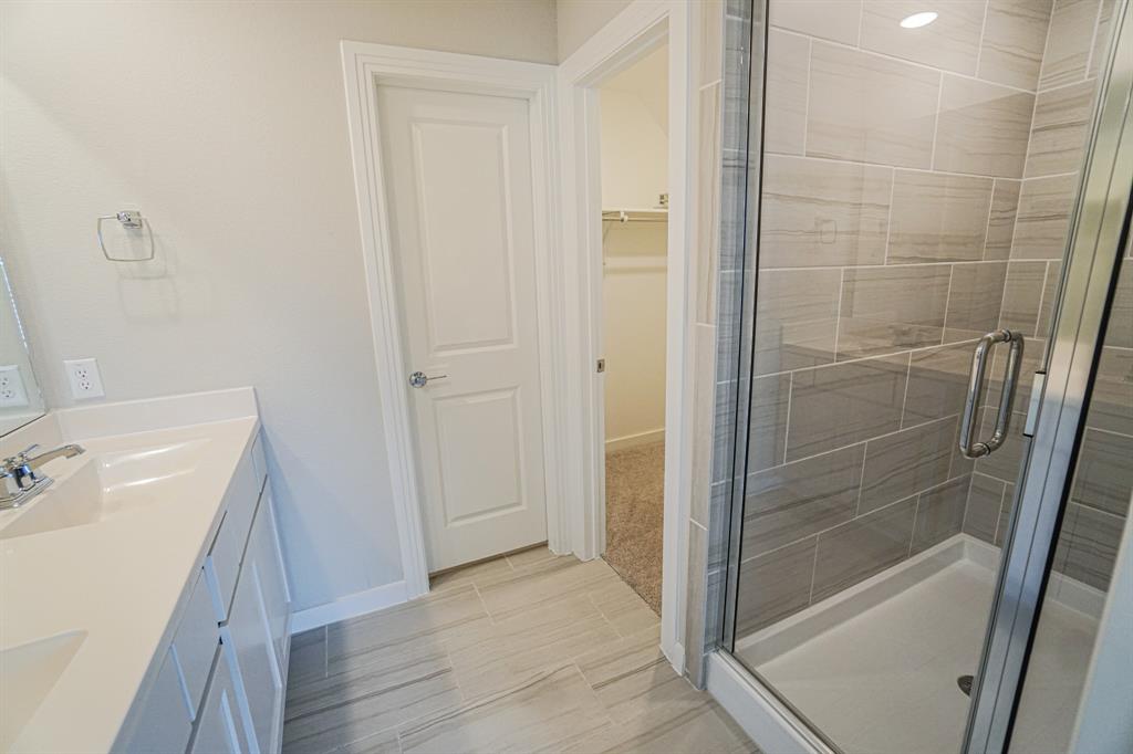 1309 Old Rocksprings Pass Mansfield, TX 76063 - Photo 26 of 36 Bathroom featuring a dual vanity with white cabinetry and integrated sinks, a walk-in shower with glass enclosure and tiled walls, and wood-finish flooring