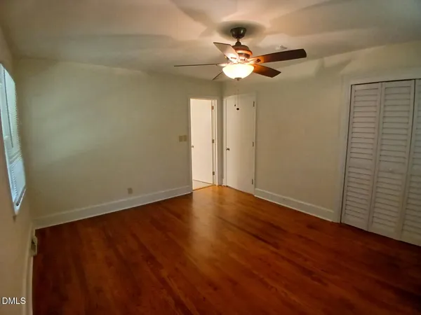 an empty room with wooden floor and fan