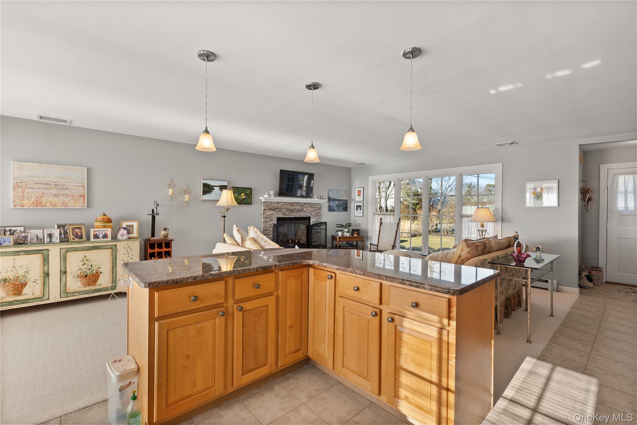 5 A Bay Road East Patchogue, NY 11772 - Photo 27 of 27 Kitchen with open floor plan, dark stone countertops, a stone fireplace, pendant lighting, and a kitchen island