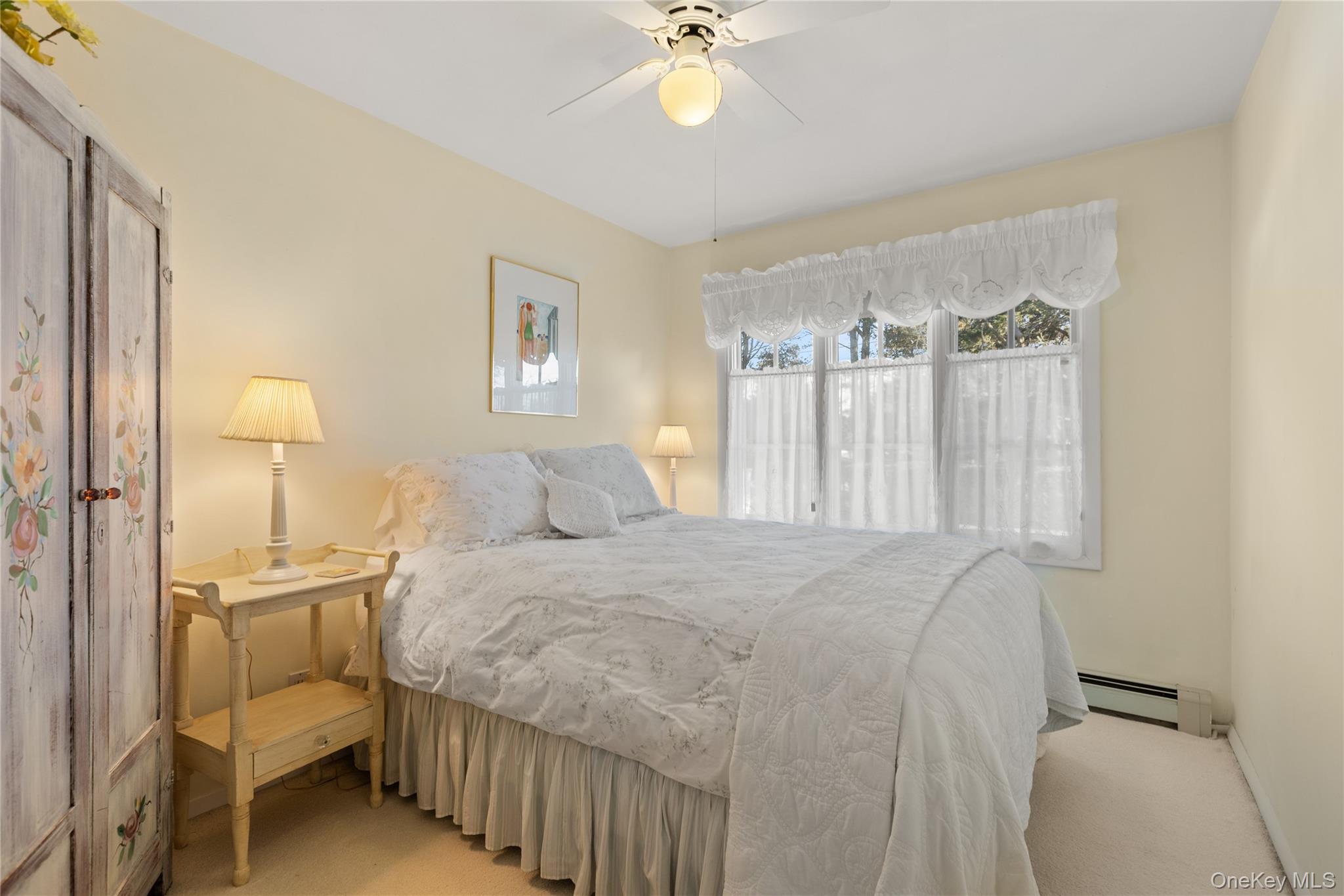 5 A Bay Road East Patchogue, NY 11772 - Photo 9 of 27 Bedroom featuring light colored carpet, baseboard heating, and ceiling fan
