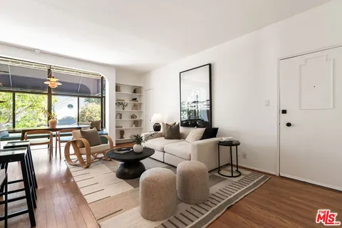 a living room with furniture large window and wooden floor
