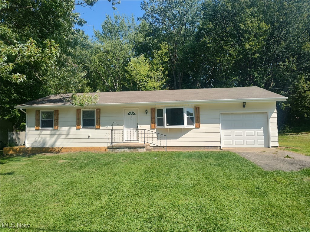 Single story home with a front yard, driveway, and a garage