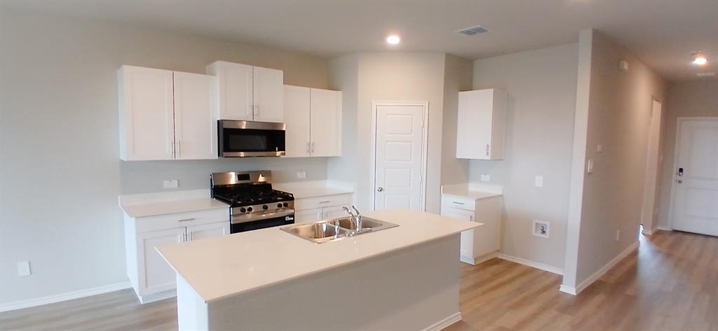 309 Potato Street Keene, TX 76059 - Photo 14 of 16 a kitchen with a sink a stove a microwave and wooden floor