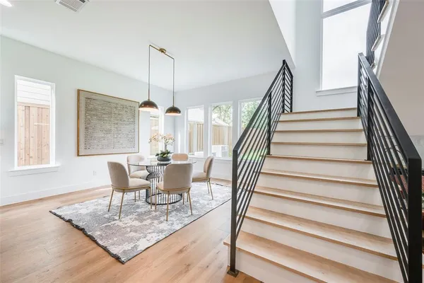 a dining room with wooden floor a chandelier a wooden table and chairs