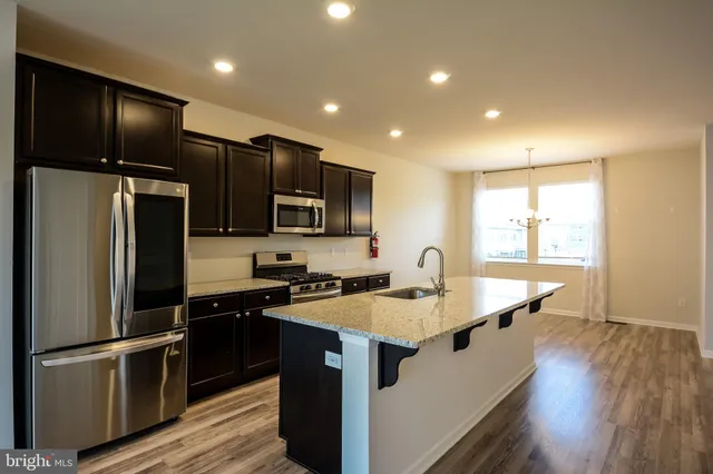 a kitchen with kitchen island granite countertop stainless steel appliances a refrigerator microwave and sink