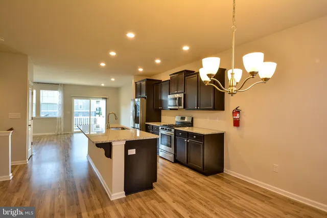 a kitchen with stainless steel appliances granite countertop a sink cabinets and wooden floor