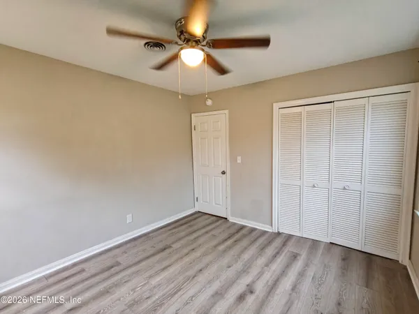 an empty room with wooden floor chandelier fan and entryway