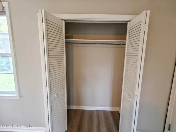 a view of an empty room with window and wooden floor