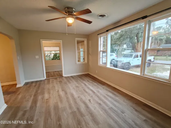 a view of empty room with wooden floor and fan