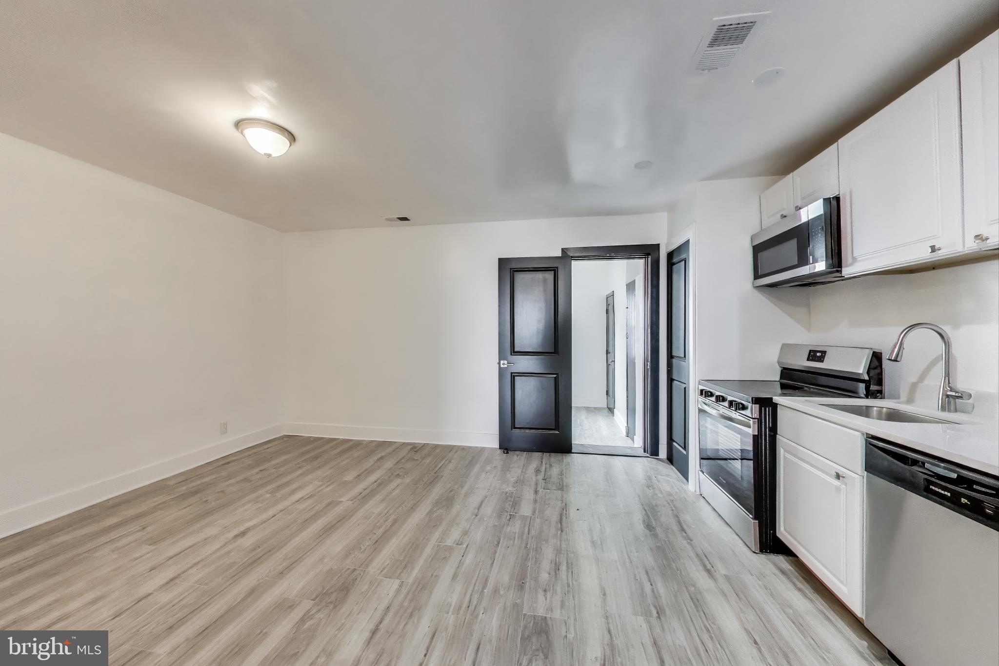 3918 10th Street Northeast, Unit 3 Washington, DC 20017 - Photo 36 of 69 a kitchen with stainless steel appliances granite countertop a stove top oven a sink dishwasher and a refrigerator with wooden floor