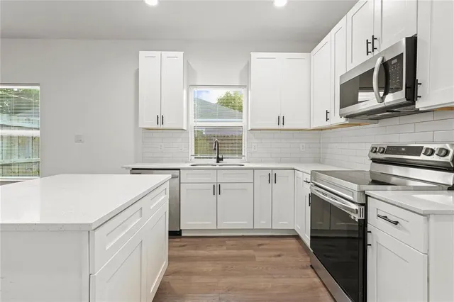 a kitchen with cabinets appliances a sink and a counter top space