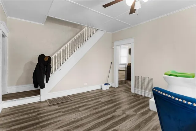 a view of an empty room with wooden floor and stairs