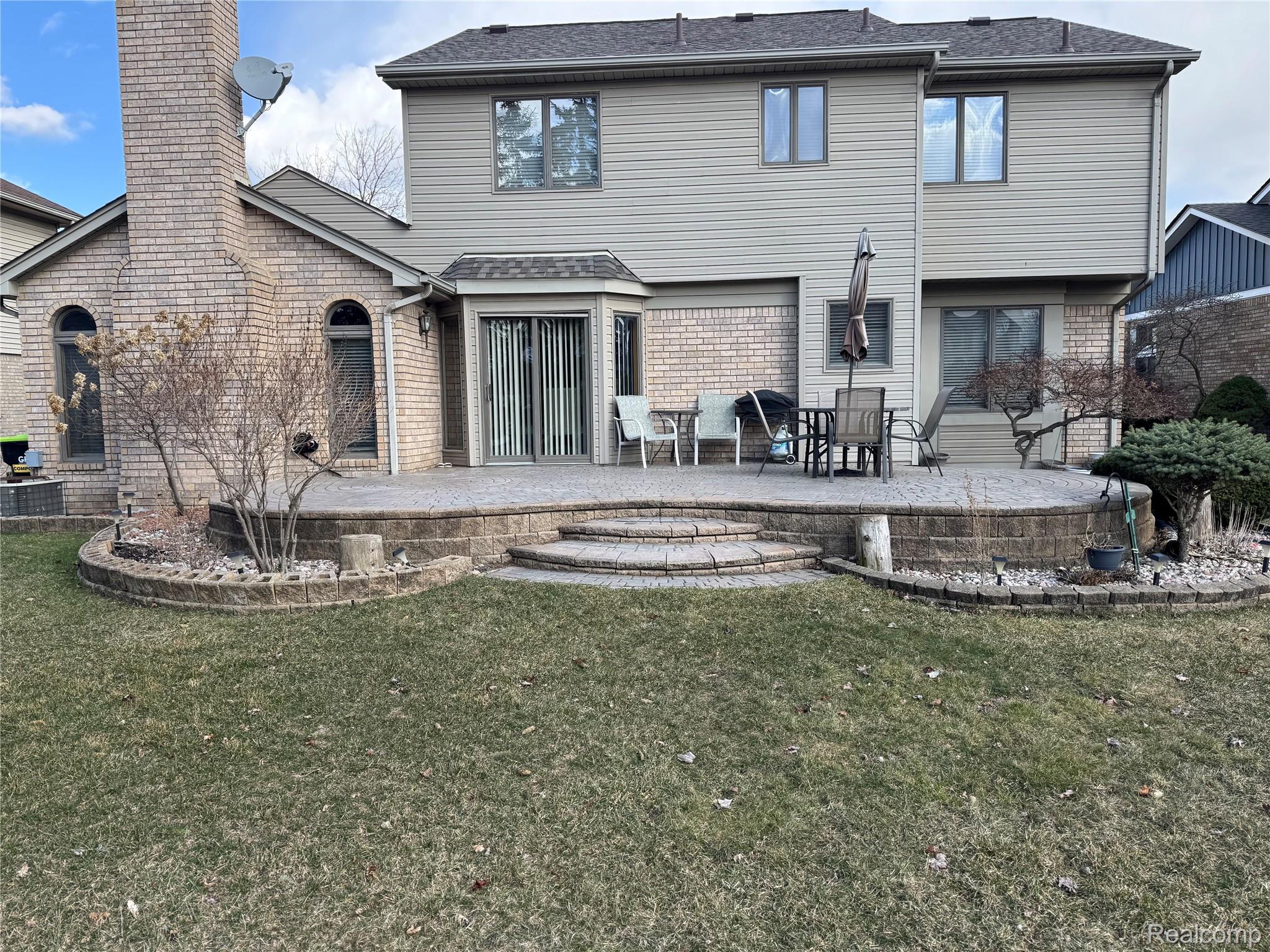 48583 Tilch Road Macomb, MI 48044 - Photo 5 of 53 Back of property with a patio, brick siding, a lawn, a chimney, and roof with shingles