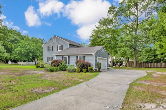 a view of a house with a big yard and large trees