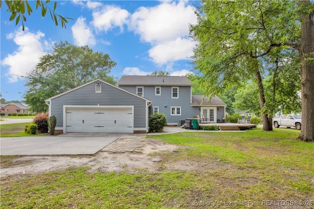 a view of house with a big yard and large trees