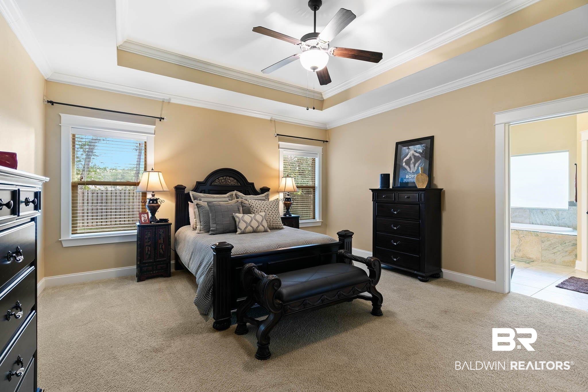19740 Bunker Loop Fairhope, AL 36532 - Photo 19 of 33 Bedroom with a tray ceiling, crown molding, light colored carpet, multiple windows, and a ceiling fan