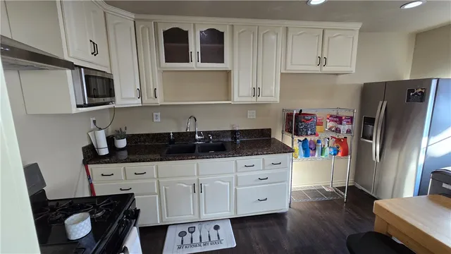a kitchen with stainless steel appliances a sink a stove a refrigerator and cabinets