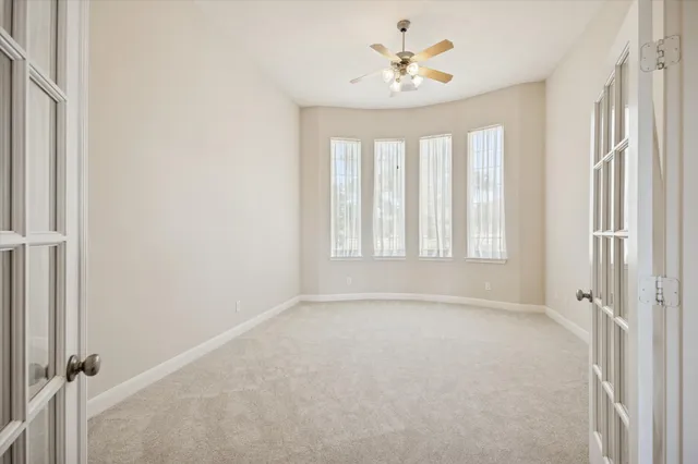 an empty room with windows and ceiling fan