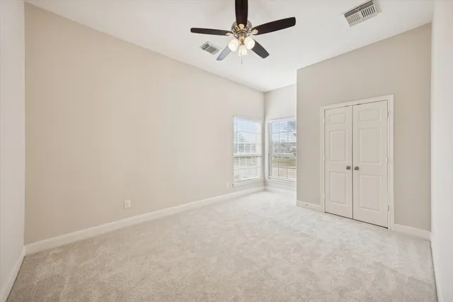 an empty room with closet and a ceiling fan