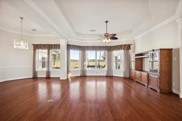 a view of an empty room with window wooden floor and a kitchen