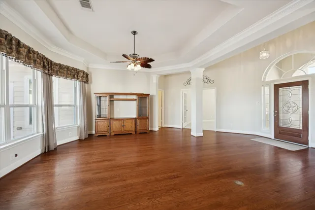 a view of an empty room with window and wooden floor