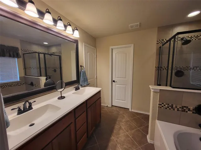 a bathroom with a double vanity sink a mirror and bathtub