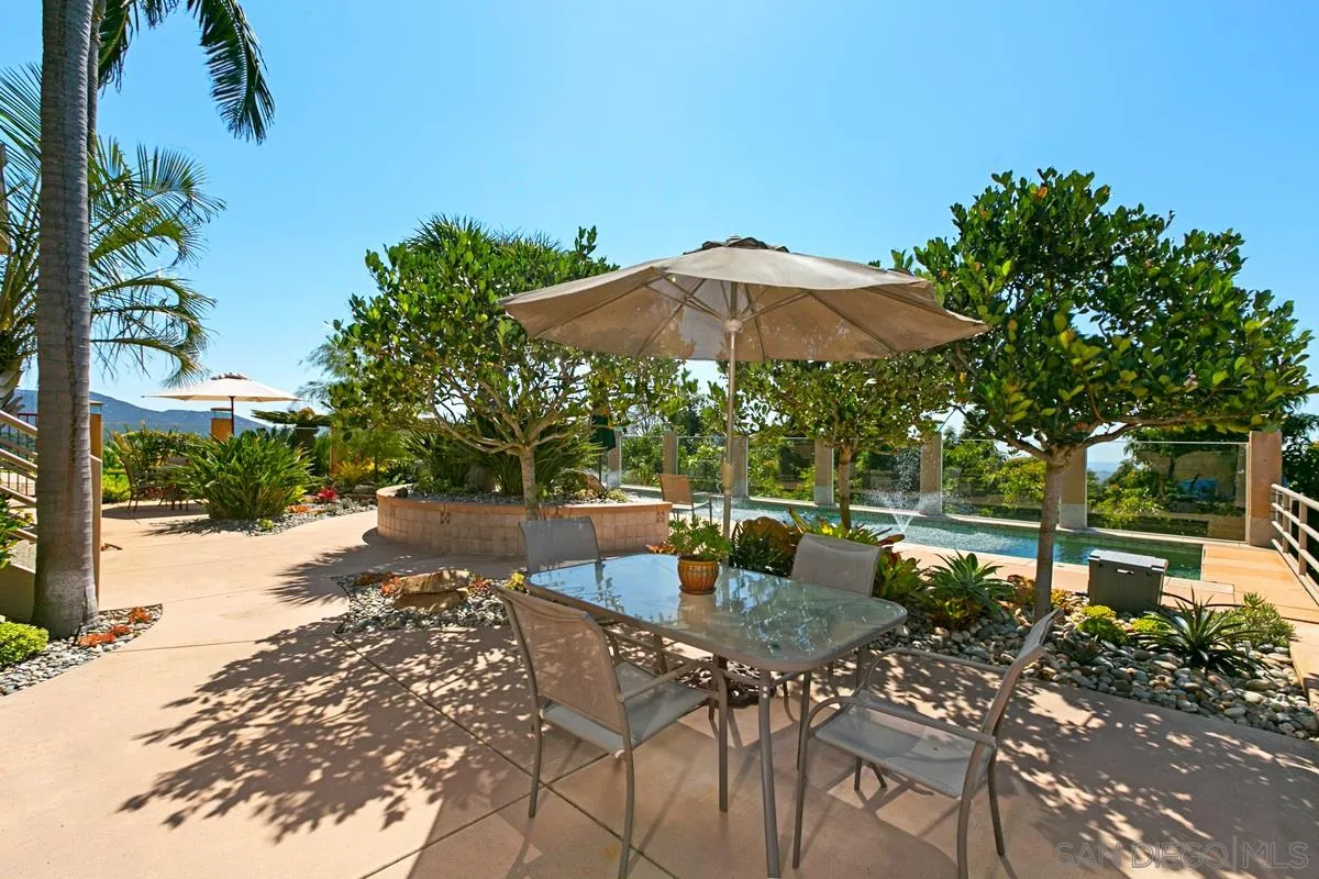1629 Wild Acres Road Vista, CA 92084 - Photo 31 of 34 a view of a patio with table and chairs under an umbrella