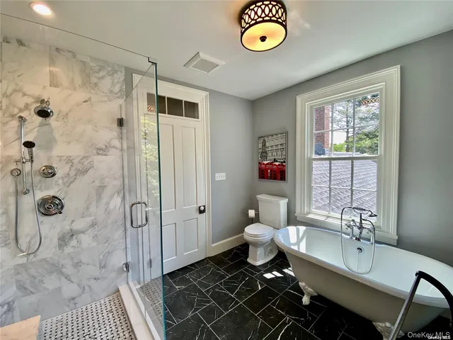 a spacious bathroom with a granite countertop sink toilet a shower and a mirror