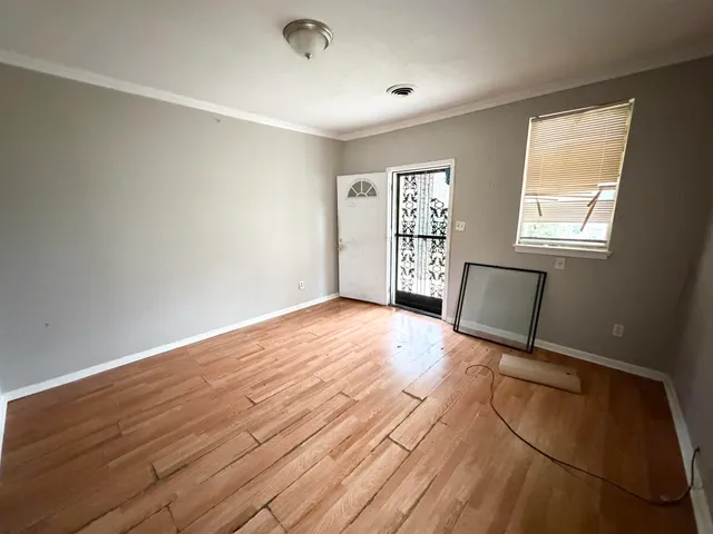 a view of an empty room with a window and wooden floor