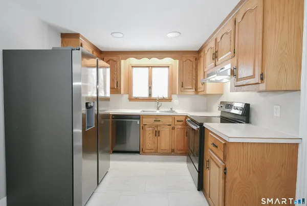 a kitchen with stainless steel appliances granite countertop a refrigerator a sink dishwasher a stove with wooden cabinets and floor