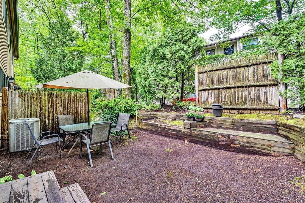 74 Meeting House Path, Unit 74 Ashland, MA 01721 - Photo 31 of 33 a backyard of a house with table and chairs under an umbrella