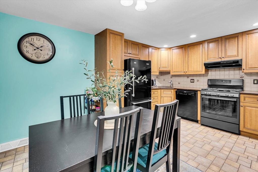 74 Meeting House Path, Unit 74 Ashland, MA 01721 - Photo 9 of 33 a kitchen with stainless steel appliances granite countertop a stove top oven a refrigerator a oven with a dining table and chairs
