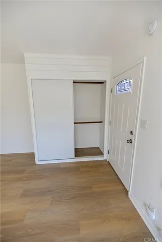 a view of an empty room with wooden floor and a hallway