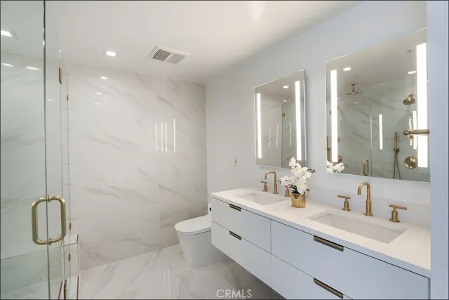 a bathroom with a double vanity sink toilet and shower